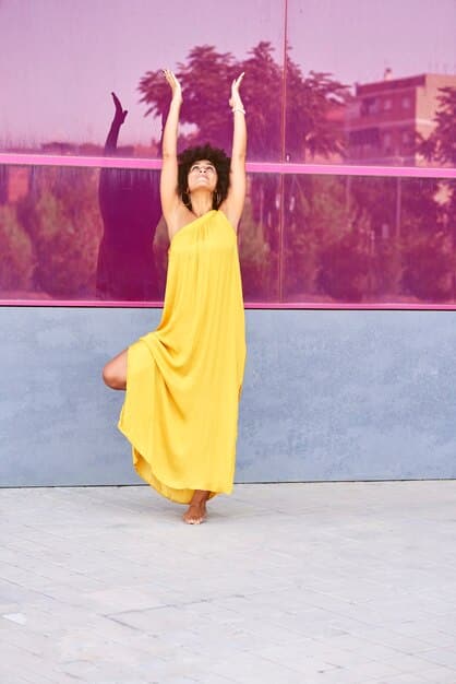 A model wearing a flowing butter yellow dress, walking on a runway with a backdrop of a sunny field, showcasing the warmth and comfort associated with the color.