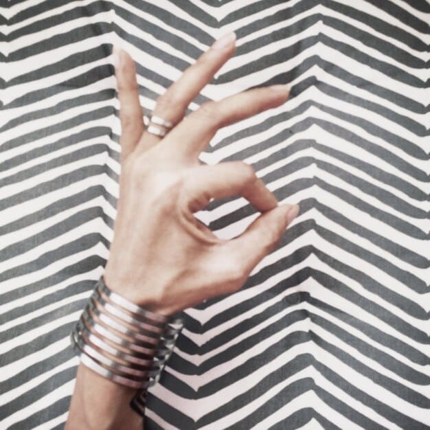 Close-up of a woman's hands displaying several minimalist rings in gold and silver, showcasing geometric designs and high-quality materials.