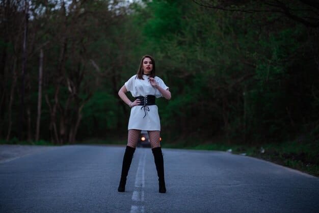 A woman with strong posture and fluid movement walking confidently in high heels during a fashion show. The environment is a stylish, brightly lit runway with photographers capturing the moment.