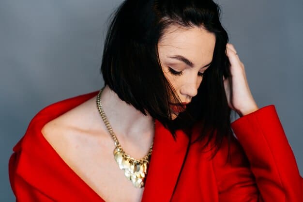 A woman wearing a monochromatic red outfit with a statement gold necklace.