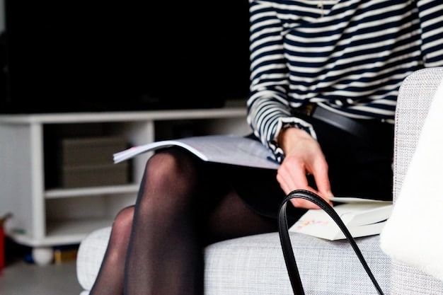 Close-up shot of a woman's hands carefully selecting accessories for a job interview outfit. She is choosing from a collection of minimalist jewelry, including a delicate necklace, stud earrings, and a classic watch. The background is a well-organized closet with neutral-colored clothing.
