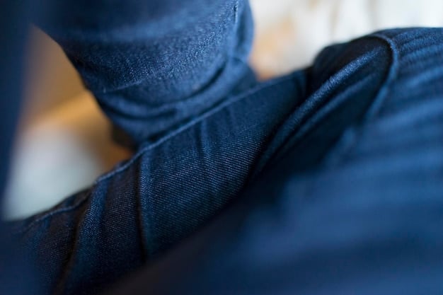 Close-up of a pair of denim jeans, showcasing its versatile texture and fit. The jeans are slightly faded and have a classic cut, emphasizing their adaptability for various occasions. The background is a blurred urban setting, hinting at travel and exploration.