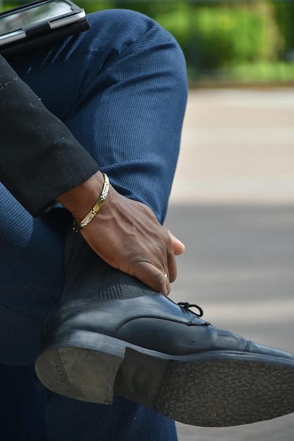 A detailed shot of a man's ankle and shoes. He is wearing dark grey dress socks that perfectly match his charcoal suit pants and complement his black leather dress shoes. The focus is on the subtle color coordination.