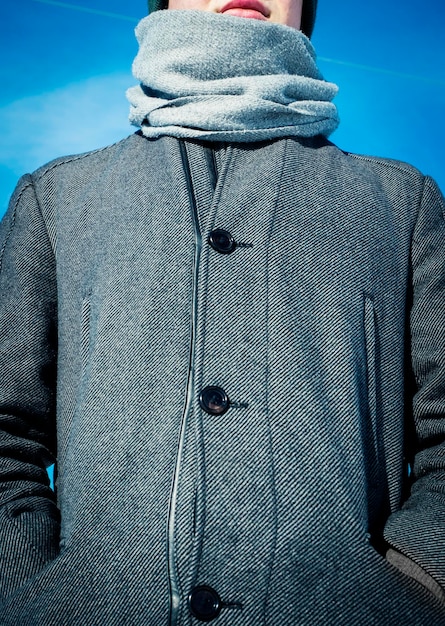 A close-up shot of a man wearing a grey wool coat, showcasing the texture of the fabric and the details of the buttons and collar.