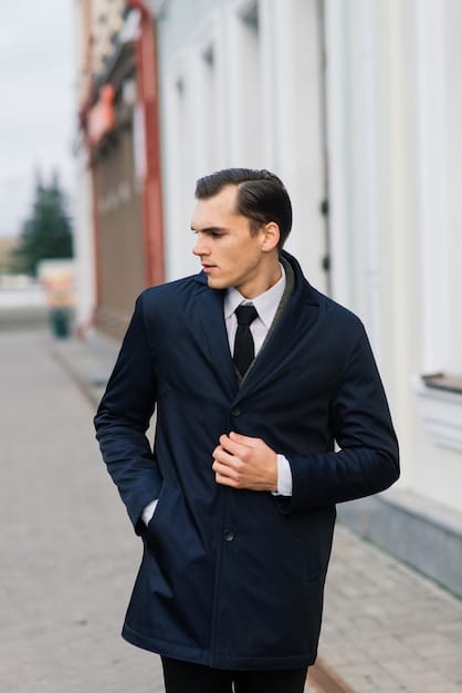 A man wearing a classic outfit consisting of a navy blue blazer, a white shirt, beige chinos, and brown leather shoes. The outfit is clean, well-fitted, and showcases the versatility of neutral colors.
