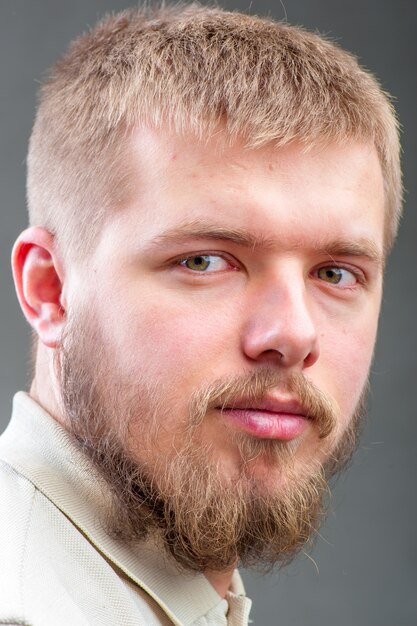 A man with a square face featuring a cropped hairstyle with slightly longer hair on top, brushed to the side and faded neatly on the sides.