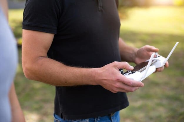 A close-up shot of a drone pilot using a remote control to operate a drone. The pilot is wearing a headset that displays real-time video feed from the drone camera, and a tablet showing a map with designated flight zones.