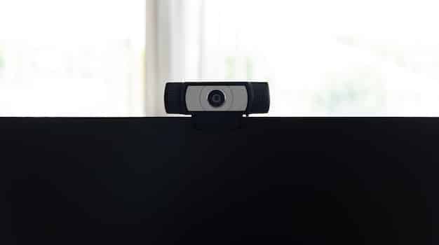 A modern webcam attached to a computer monitor, with a crisp, clear image displayed on the screen. The background shows a well-lit home office.