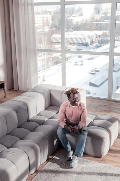 A person looking frustrated while trying to use a complex and glitchy augmented reality home decorating app on their smartphone; the virtual furniture flickers and doesn't align properly with the real-world environment, showcasing the app's lack of practicality and user-friendliness.