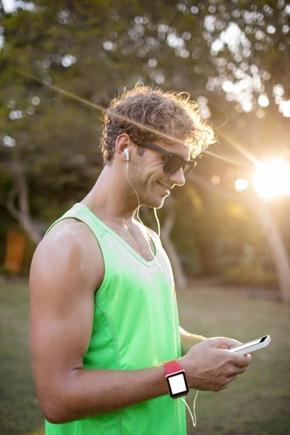 A runner wearing a GPS running watch, focusing on the watch screen displaying pace and distance data during an outdoor run in a park. The sunlight is catching the screen as he runs.