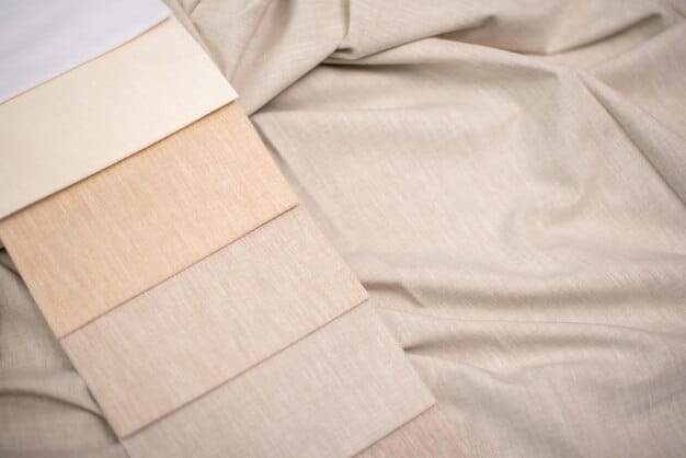 A closeup of fabric swatches in linen and chino materials in various neutral colors like beige, white, grey, and light blue, arranged on a wooden table, showcasing the texture and color options.
