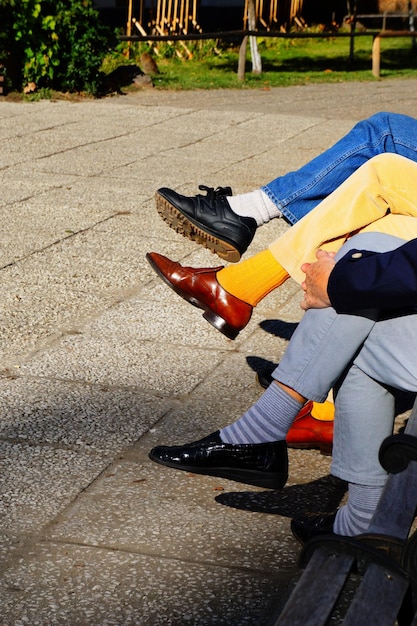 A close-up of a man wearing mismatched shoes with his outfit. One shoe is a formal leather shoe, while the other is a vibrant sports shoe, highlighting the fashion faux pas.