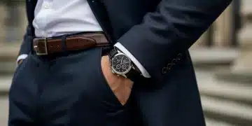 Hombre con traje elegante, reloj de lujo y cinturón de cuero, representando una inversión inteligente en accesorios masculinos para 2025.