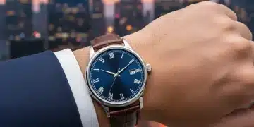Elegant watch on a man's wrist with city skyline background, symbolizing luxury and investment.